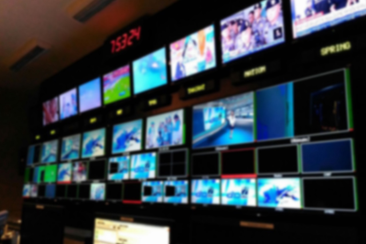 A blurred image of a large bank of tv screens and monitors