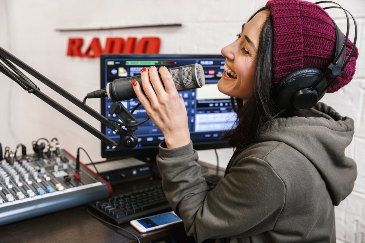 a person in a hooded sweatshirt talking emphatically into a microphone